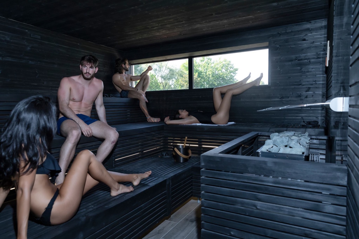 Sauna finlandese in legno scuro affacciata sul verde