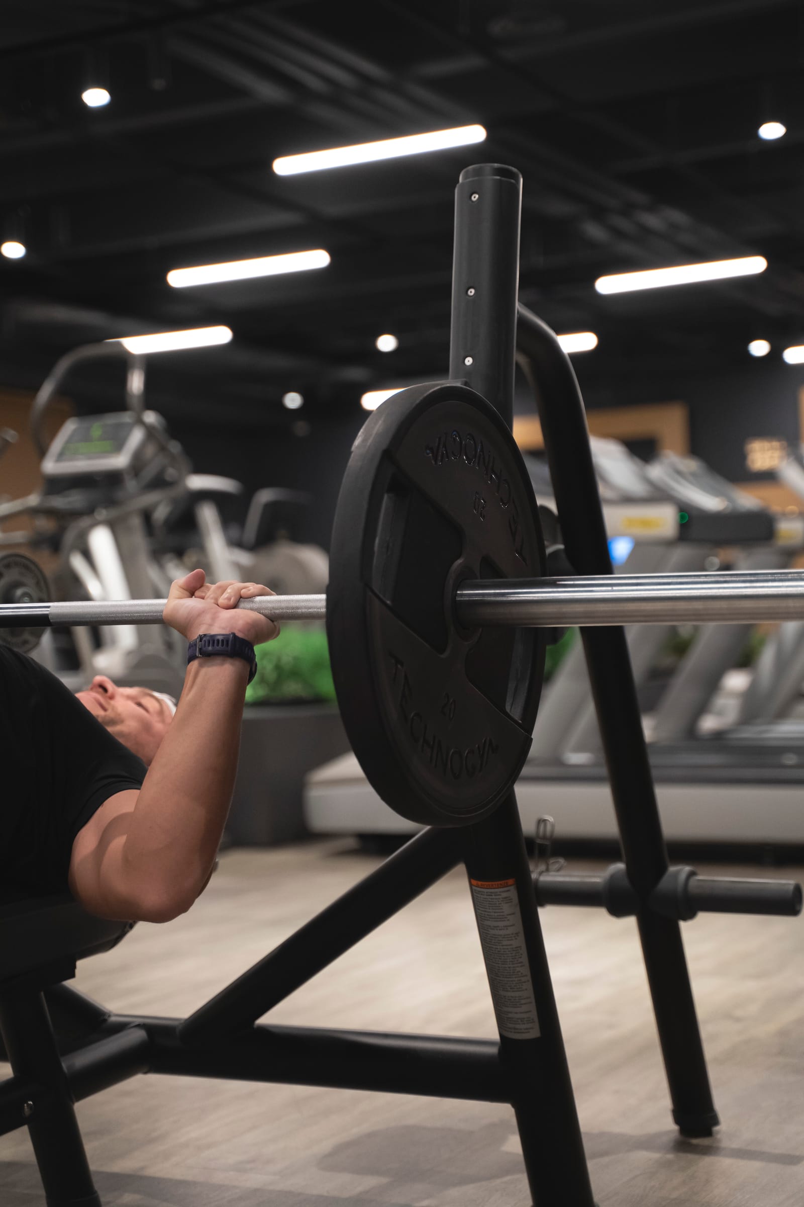 Primo piano del bilanciere con i dischi Technogym durante una distensione su panca
