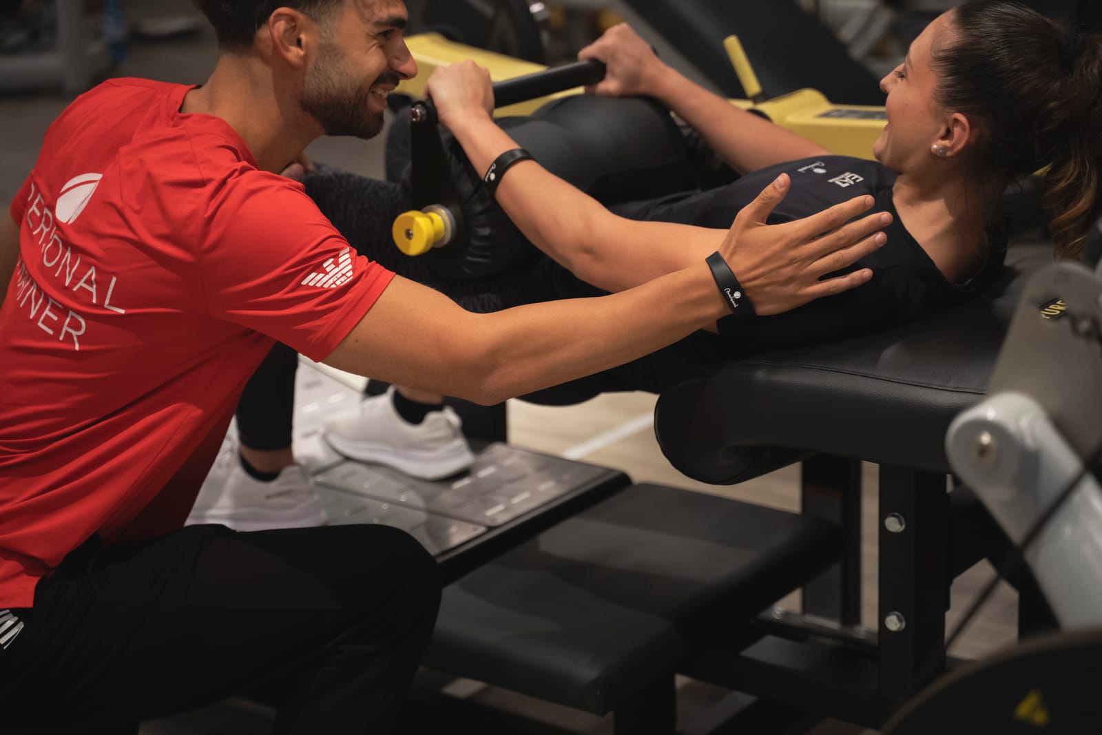 Il personal trainer corregge la posizione di una cliente durante un hip thrust