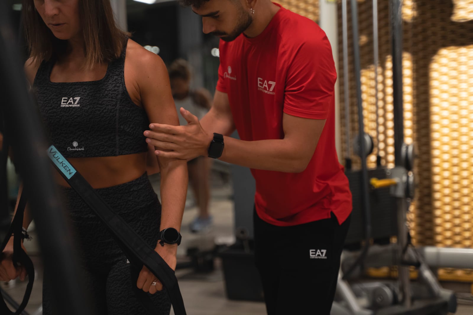Il personal trainer guida una cliente in un esercizio con le cinghie TRX