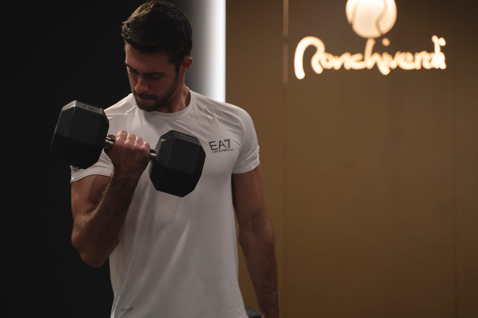 Curl con manubrio nella Skill Area, con il logo Ronchiverdi illuminato alle spalle